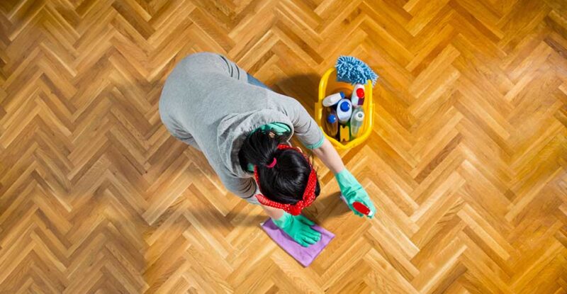Profissional higienizando o chão. Veja como economizar com soluções caseiras para limpeza de pisos!