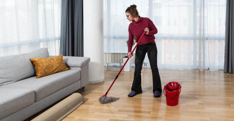 Mulher indo limpar piso encerado. Veja dicas para garantir qualidade!