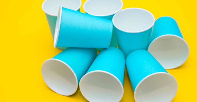 Produtos descartáveis para festas infantis espalhados sobre superfície amarela.
