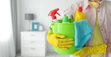 Pessoa segurando balde com produtos, mostrando que limpeza ajuda a melhorar a saúde mental.