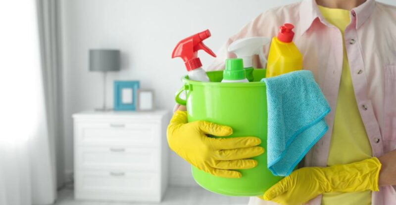 Pessoa segurando balde com produtos, mostrando que limpeza ajuda a melhorar a saúde mental.
