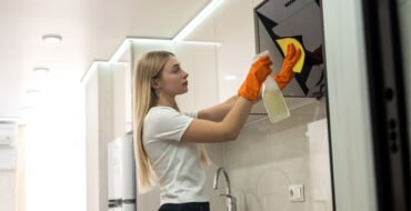 Uma mulher limpa o exaustor, garantindo a limpeza da cozinha na empresa.